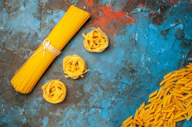 Kostenloses Foto draufsicht auf verschiedene italienische pasta für die zubereitung des abendessens auf blauem hintergrund