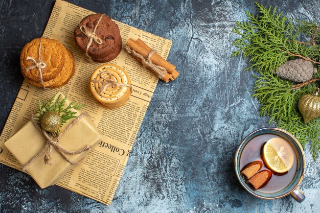 Draufsicht auf verschiedene leckere Kekse mit Geschenk und Tee auf hellem Hintergrund