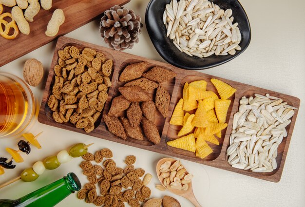 Draufsicht auf verschiedene salzige Biersnacks mit einem Becher Bier auf Weiß