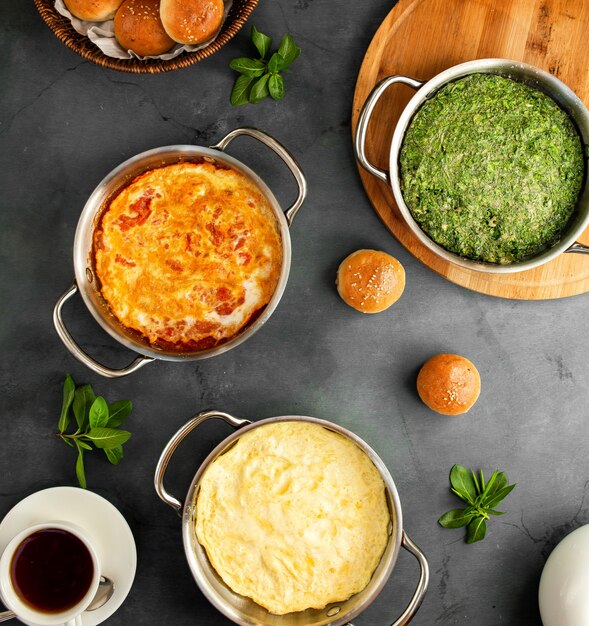 Draufsicht auf verschiedene Spiegeleifrühstückseier mit klassischem Tomatenomelett und aserbaidschanischem Kuku auf Schwarzem