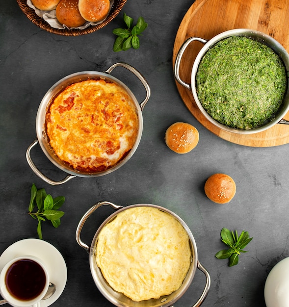 Draufsicht auf verschiedene Spiegeleifrühstückseier mit klassischem Tomatenomelett und aserbaidschanischem Kuku auf Schwarzem