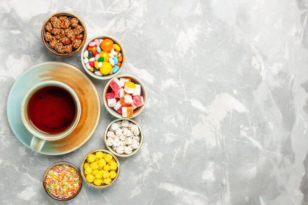 Draufsicht auf verschiedene süße Bonbons mit Marshmallows und Tee auf weißer Oberfläche