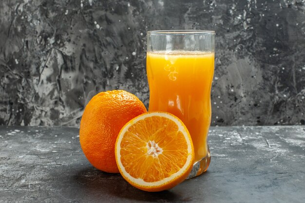 Draufsicht auf Vitaminquelle geschnitten und ganze frische Orangen und Saft auf grauem Hintergrund