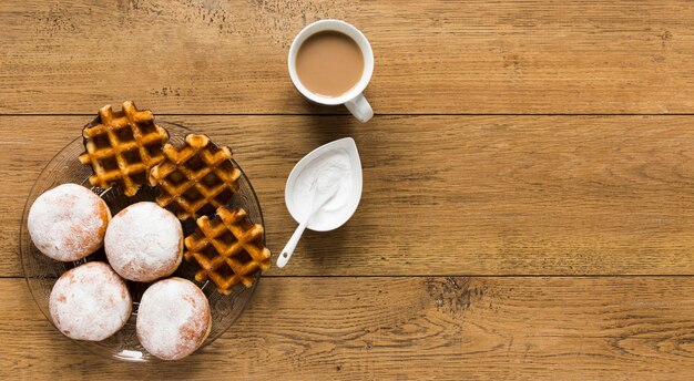 Draufsicht auf Waffeln mit Donuts und Kaffee