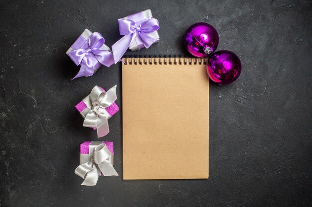 Kostenloses Foto draufsicht auf weihnachtsschmuck und notizbuch mit geschenken auf schwarzem hintergrund