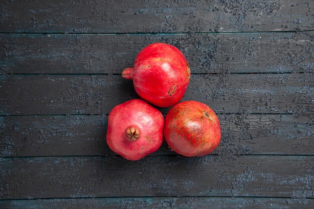 Draufsicht aus der Ferne Granatäpfel auf Tisch drei rote Granatäpfel auf dunklem Tisch