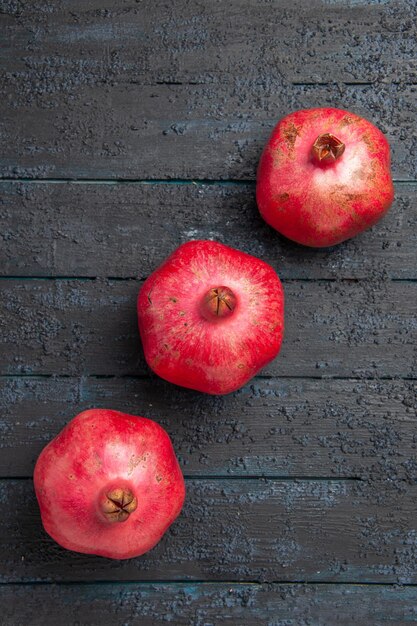 Draufsicht aus der Ferne rote Granatäpfel reife Granatäpfel in der Mitte des grauen Holztisches