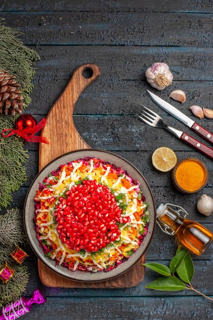 Draufsicht aus der Ferne Schneidebrett Weihnachtsgericht auf dem Holzbrett neben den Schüsseln mit Gewürzen Knoblauchgabelmesser und Flasche Öl