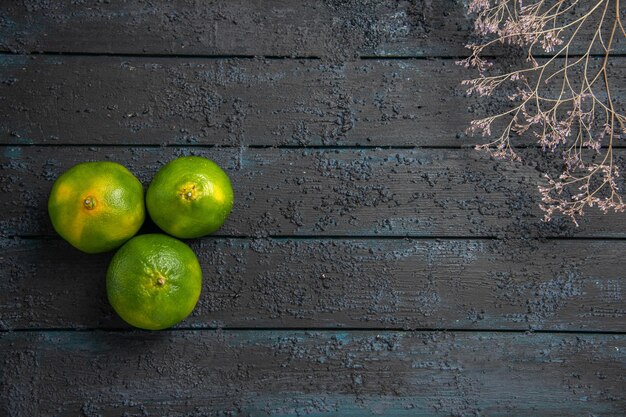 Draufsicht aus der Ferne Äste und Limetten drei Limetten auf dem Tisch mit Ästen