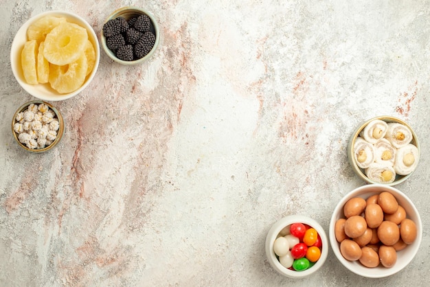 Draufsicht aus der Ferne Zitronenkuchen sechs Schüsseln mit Bonbons rechts und links des weißen Hintergrunds