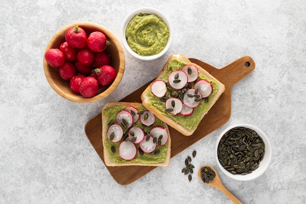 Draufsicht Avocado Toast mit Radieschen und Samen auf Schneidebrett