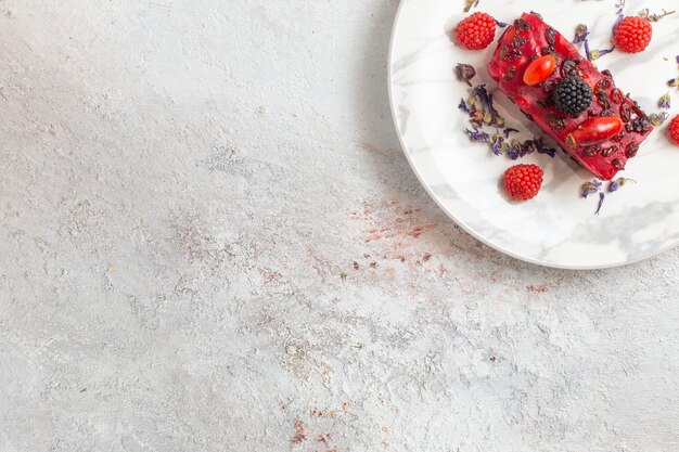 Draufsicht Beerenkuchenscheiben mit roter cremiger Glasur und frischen Beeren auf weißer Oberfläche