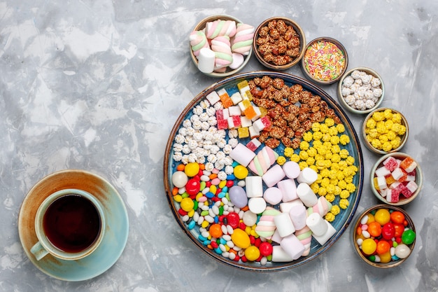 Draufsicht Bonbon Zusammensetzung verschiedenfarbige Bonbons mit Marshmallow in Töpfen mit Tee auf weißem Schreibtisch Zuckersüßigkeiten Bonbon süße Konfiture