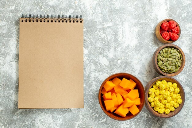 Draufsicht Bonbons und Kürbis mit Samen und Notizblock auf weißem Hintergrund Copybook Farbe Süßigkeitsfrucht