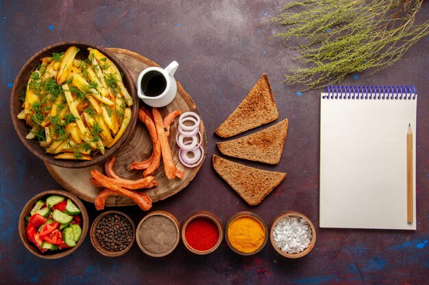 Draufsicht Bratkartoffeln mit Gewürzbrot und verschiedenem Gemüse auf dem dunklen Schreibtisch