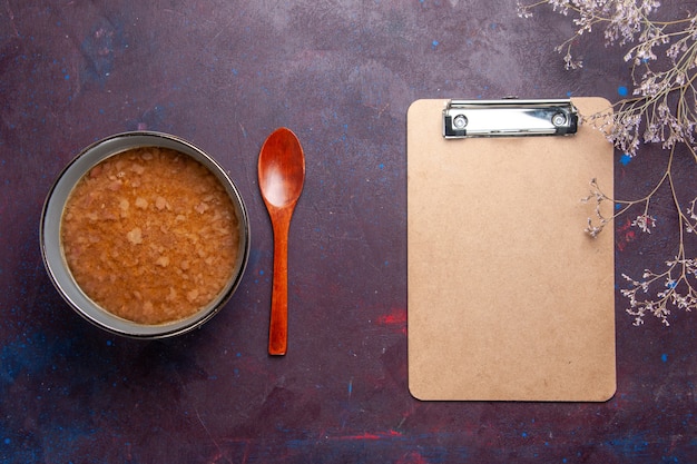 Draufsicht braune Suppe innerhalb Platte mit Notizblock auf dunkler Oberfläche Suppe Gemüsemehl Lebensmittel Küchenöl