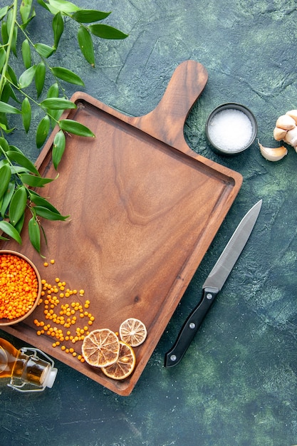 Draufsicht brauner hölzerner Schreibtisch mit orangefarbenen Linsen auf der dunkelblauen Oberfläche der alten Küche färbt Fleischfleischmetzger-Küchenmesserfutter