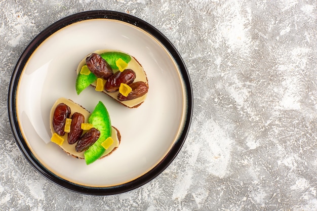 Draufsicht Brot Toast mit Gurke und getrockneten Pflaumen in Platte auf weißem Schreibtisch Brot Toast Sandwich Essen Frühstück