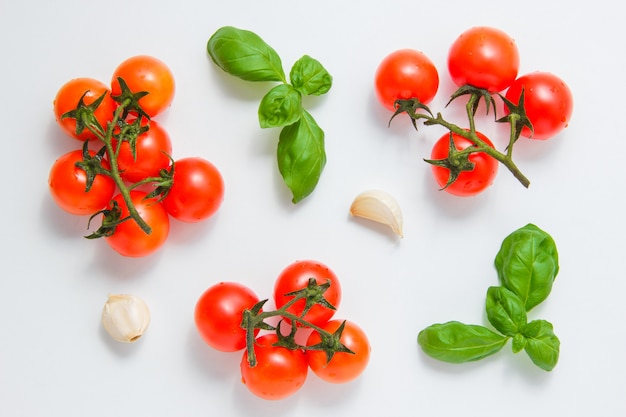 Draufsicht-Bündel von Tomaten mit Knoblauch und Blättern auf weißem Hintergrund. horizontal