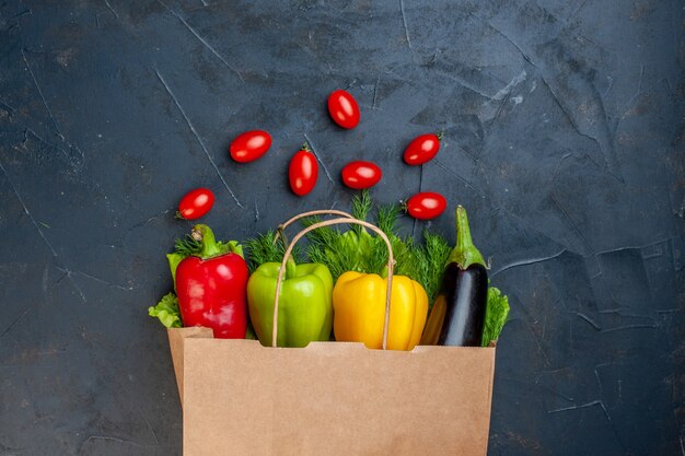 Draufsicht bunte Paprika Auberginengrün in Papiertüte Kirschtomaten auf dunklem Hintergrund