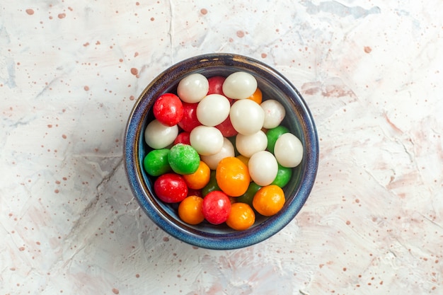 Draufsicht bunte süße Bonbons innerhalb der Platte auf weißer Tischfarbe süßer Kandiszucker