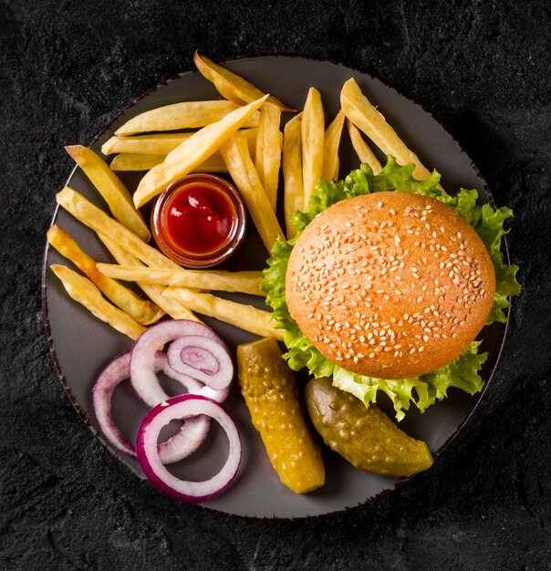 Draufsicht Burger und Pommes auf Teller mit Gurken