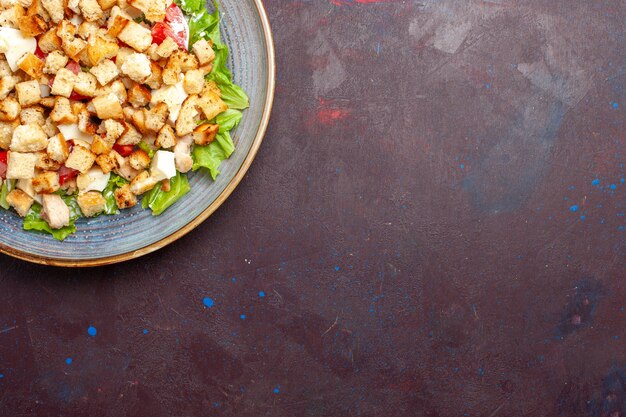 Draufsicht Caesar Salat mit geschnittenem Gemüse und Zwieback auf der dunklen Wand Gemüse Salat Essen Mittagessen Mahlzeit Zwieback