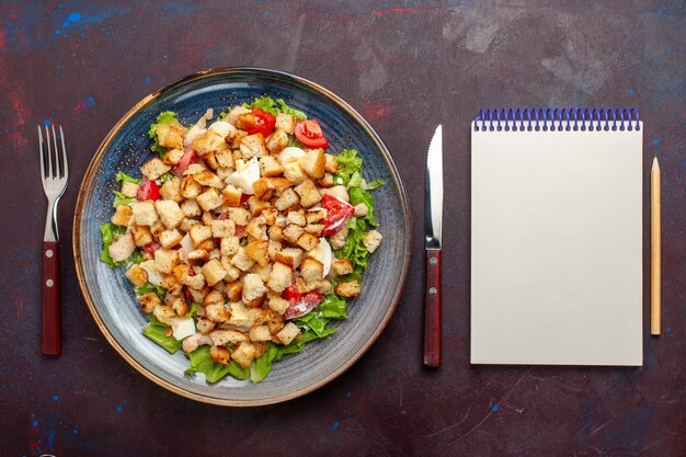 Draufsicht Caesar Salat mit geschnittenem Gemüse und Zwieback auf dunkler Wand Gemüsesalat Essen Mittagessen Mahlzeit Zwieback Geschmack Foto