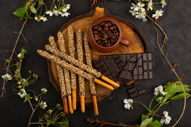 Draufsicht Candy Sticks Schokoladenkaffeesamen auf dem braunen Schreibtisch und dunkel