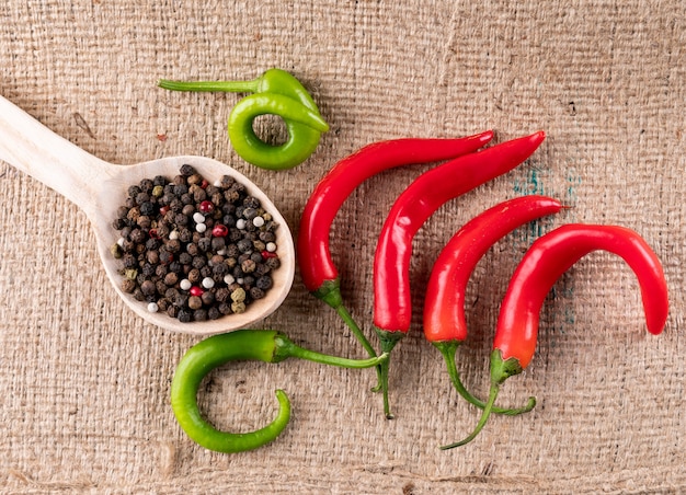 Kostenloses Foto draufsicht chili pfeffer mit gewürzen auf holzlöffel auf beigem leinen horizontal