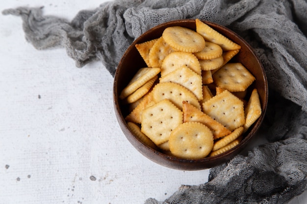 Draufsicht-Cracker und Chips innerhalb der braunen Platte auf dem hellen Hintergrund-Snack-Knackknacker