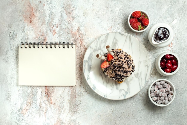 Kostenloses Foto draufsicht cremiger köstlicher kuchen mit erdbeeren und bonbons auf weißer oberfläche