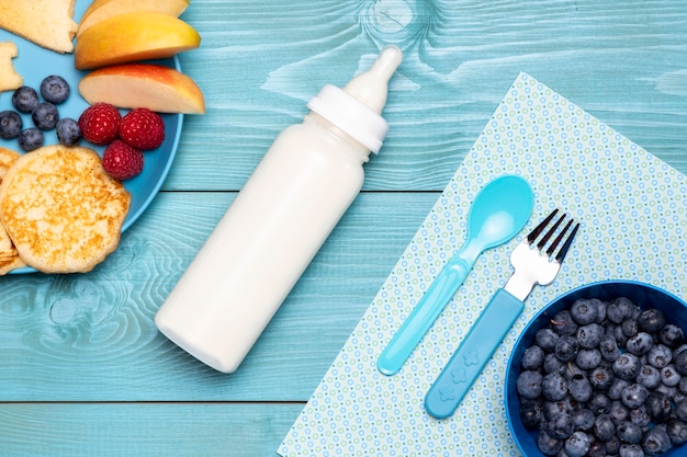 Draufsicht der Babyflasche mit Blaubeeren und Nahrung