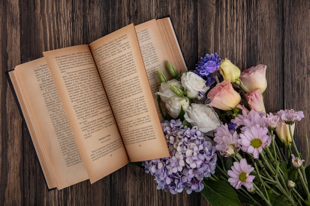 Kostenloses Foto draufsicht der blumen und des offenen buches auf hölzernem hintergrund