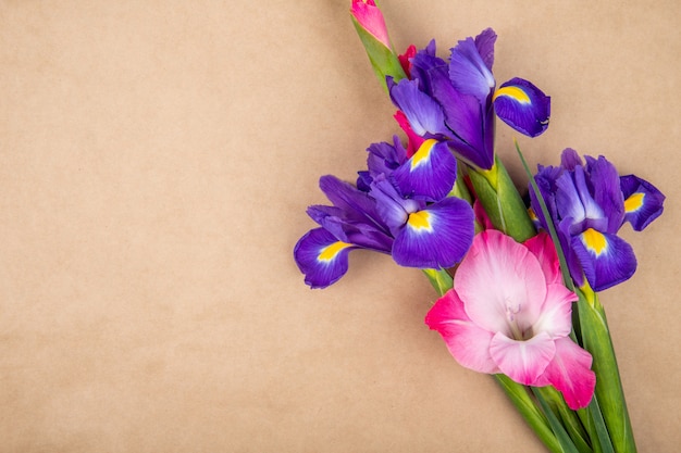 Draufsicht der dunklen lila und rosa Farbe Iris und Gladiolenblumen lokalisiert auf braunem Papierbeschaffenheitshintergrund mit Kopienraum