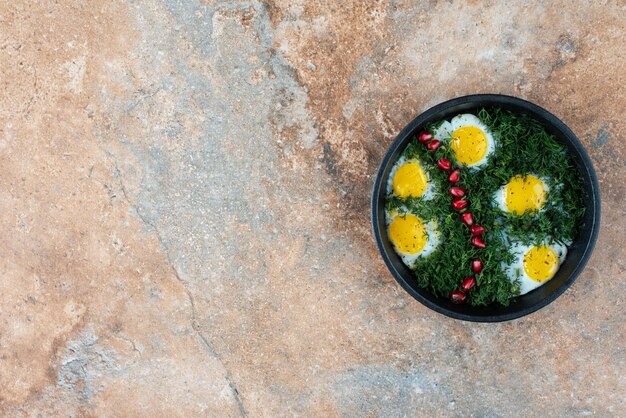 Draufsicht der dunklen Pfanne mit Omelett und Grüns