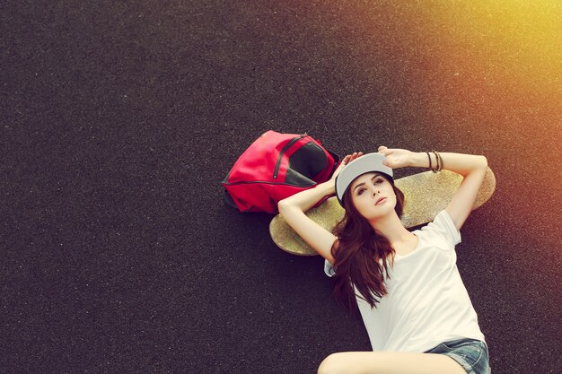 Draufsicht der Frau auf dem Boden mit Skateboard liegend