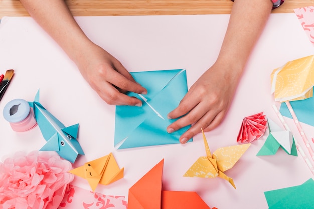 Draufsicht der Frauenhand Origamihandwerk über Tabelle machend