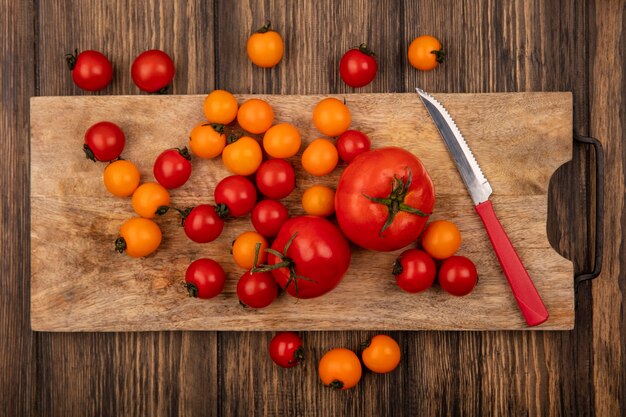 Draufsicht der frischen bunten Tomaten lokalisiert auf einem hölzernen Küchenbrett mit Messer auf einer hölzernen Oberfläche