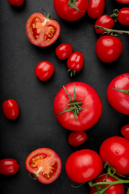 Draufsicht der frischen reifen Tomaten verstreut auf schwarzem Hintergrund