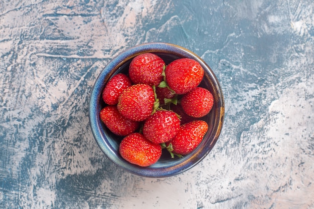 Draufsicht der frischen roten Erdbeeren innerhalb Platte auf heller Oberfläche
