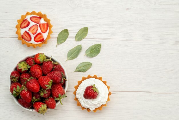 Draufsicht der frischen roten Erdbeeren weich und köstliche Beeren innerhalb Platte mit Kuchen auf hellem Schreibtisch, Fruchtbeere rot frisch