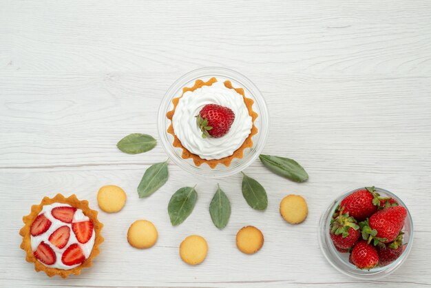 Draufsicht der frischen roten Erdbeeren weich und köstliche Beeren mit Kuchen und Keksen auf hellem Schreibtisch, Fruchtbeere frisch