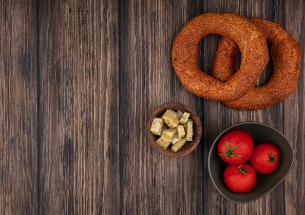 Draufsicht der frischen türkischen Bagels mit gehackten Scheiben des Käses und der Tomaten auf einer Schüssel auf einem hölzernen Hintergrund mit Kopienraum