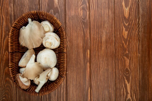 Draufsicht der frischen weißen Pilze in einem Weidenkorb auf rustikalem Holz mit Kopienraum