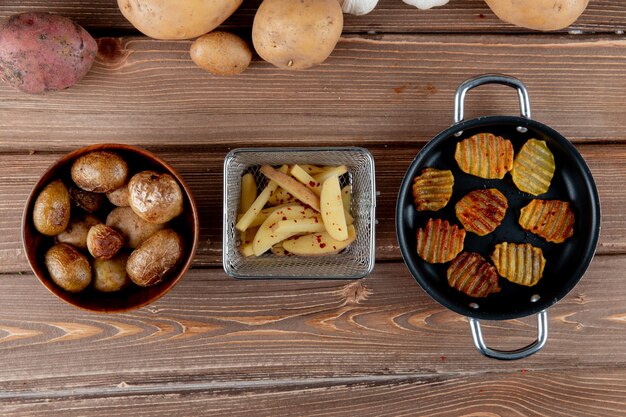 Draufsicht der gebackenen geschnittenen Kartoffel mit Kartoffelchips auf hölzernem Hintergrund mit Kopienraum