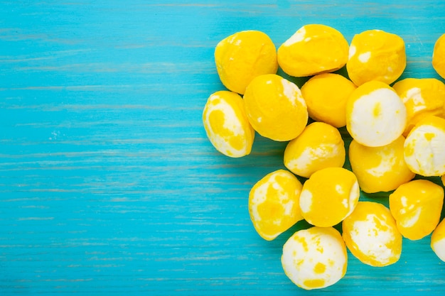 Draufsicht der gelben süßen Zuckersüßigkeiten auf blauem hölzernem Hintergrund mit Kopienraum
