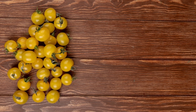Draufsicht der gelben Tomaten auf der linken Seite und auf dem Holztisch