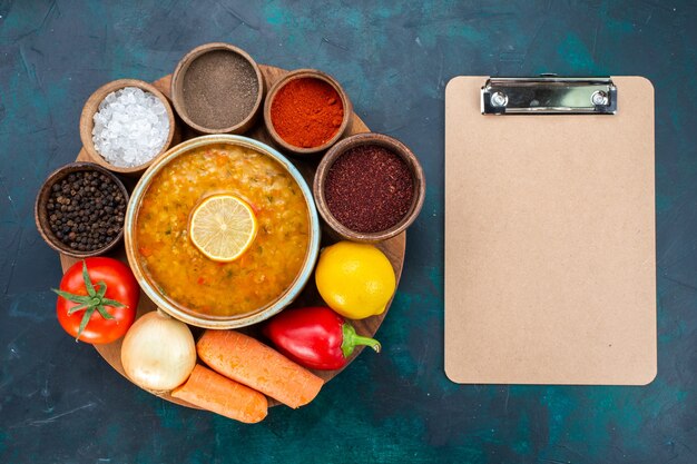 Kostenloses Foto draufsicht der gemüsesuppe mit zitrone zusammen mit gewürzen und frischem gemüse auf dunkelblauer oberfläche