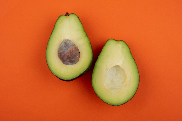 Draufsicht der gesunden frischen köstlichen Avocado auf orange Oberfläche